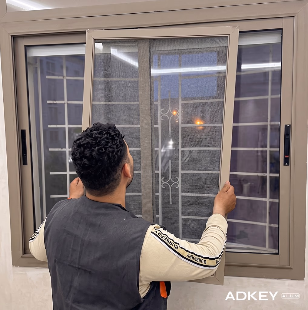 Technicien posant une moustiquaire aluminium sur mesure sur une fenêtre coulissante à Tanger — Aluminium Tanger