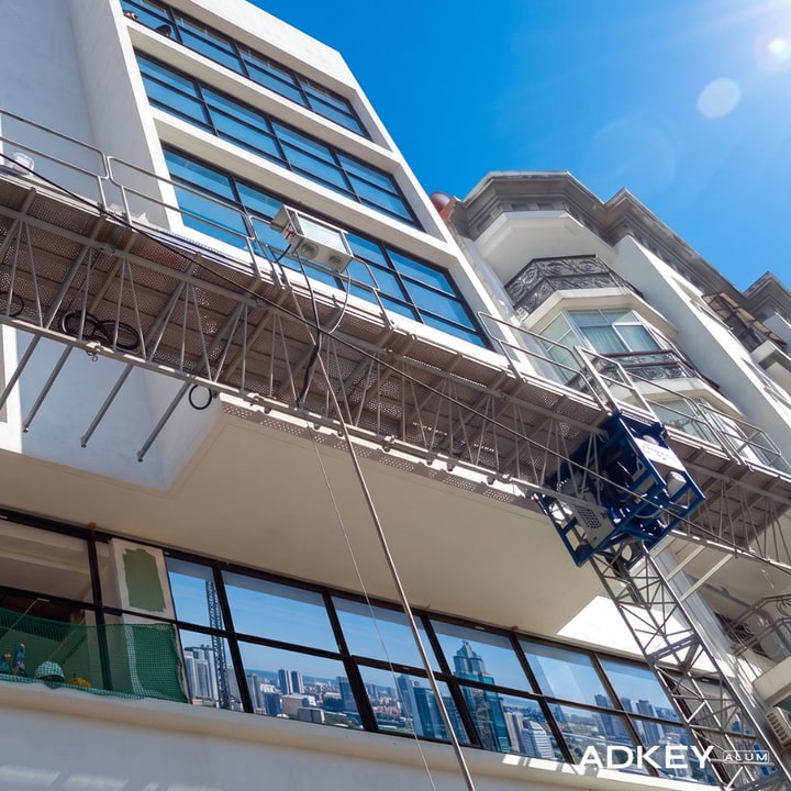 Pose de fenêtres aluminium sur une façade d'immeuble en hauteur depuis une nacelle de chantier à Asilah — AdKey Aluminium